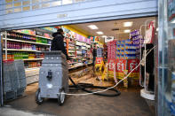 An employee uses a water vacuum to remove floodwater in a Poundland shop in Pontypridd. (PA)