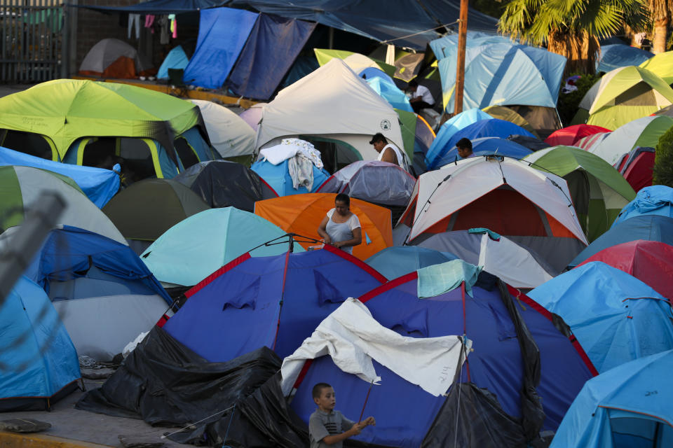 In this Oct. 11, 2019 photo, migrants wake up at a camp set up by migrants waiting near a legal port of entry bridge in Matamoros, Mexico. In years past, migrants seeking asylum in the United States moved quickly through this violent territory on their way to the U.S., but now due to Trump administration policies, they remain here for weeks and sometimes months as they await their U.S. court dates, often in the hands of gangsters who hold Tamaulipas state in a vice-like grip. (AP Photo/Fernando Llano)