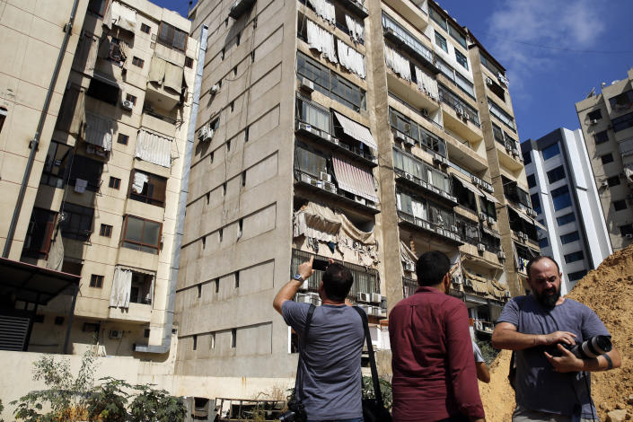 Journalists take pictures of the 11th-floor building that houses Hezbollah's media office as well as nearby buildings suffered minor damage and broken glass in a southern suburb of Beirut, Lebanon, Sunday, Aug. 25, 2019. Two Israeli drones crashed in a Hezbollah stronghold in the Lebanese capital overnight without the militants firing on them, a spokesman for the group said Sunday, saying the first fell on the roof of a building housing Hezbollah's media office while the second landed in a plot behind it. (AP Photo/Bilal Hussein)
