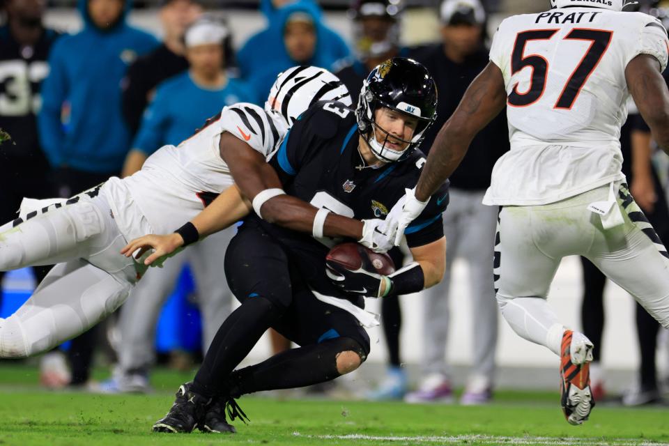 Cincinnati Bengals safety Jordan Battle (27) wraps up with Jacksonville Jaguars quarterback C.J. Beathard (3) as linebacker Germaine Pratt (57) looks on during the fourth quarter of a regular season NFL football matchup Monday, Dec. 4, 2023 at EverBank Stadium in Jacksonville, Fla. The Cincinnati Bengals defeated the Jacksonville Jaguars 34-31 in overtime. [Corey Perrine/Florida Times-Union]