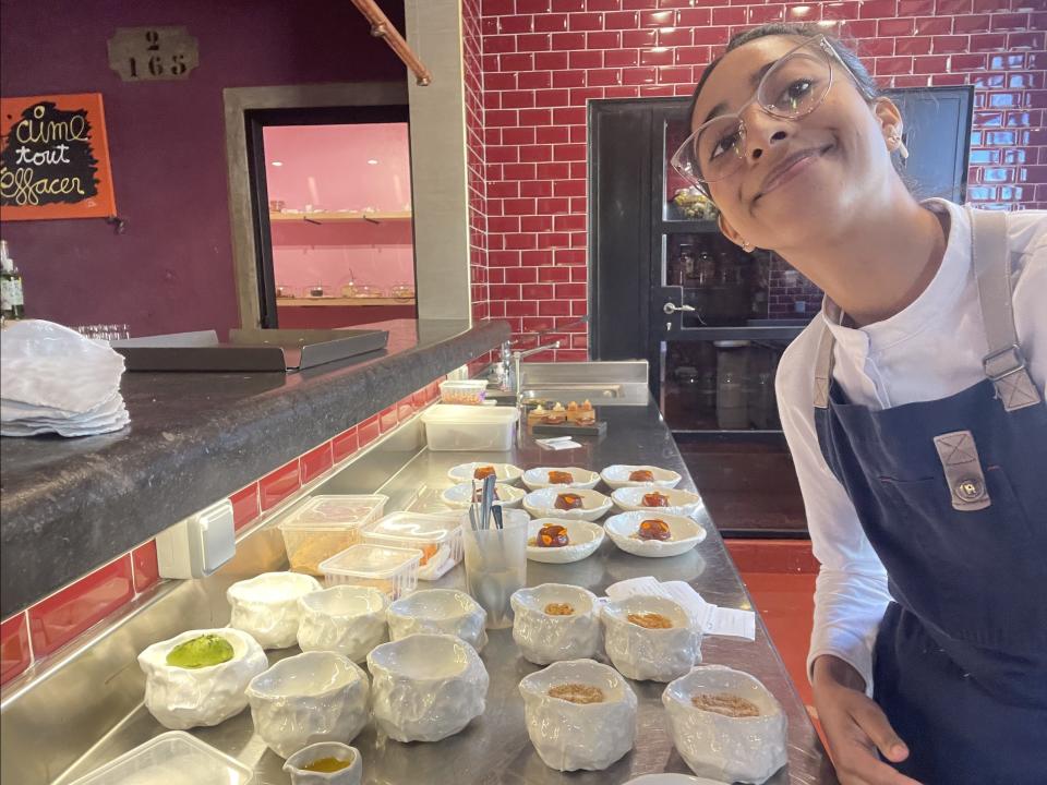 The writer smiles and stands next to a selection of plates pastries