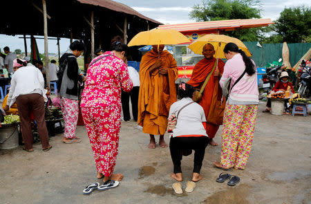 Workers donate to monks before their shift at Complete Honour Footwear Industrial, a footwear factory owned by a Taiwan company, in Kampong Speu, Cambodia, July 4, 2018. REUTERS/Ann Wang