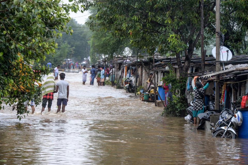 Residents make their way through floodwaters on a street following heavy rains in Hyderabad on October 14, 2020. (Photo by NOAH SEELAM / AFP) (Photo by NOAH SEELAM/AFP via Getty Images)