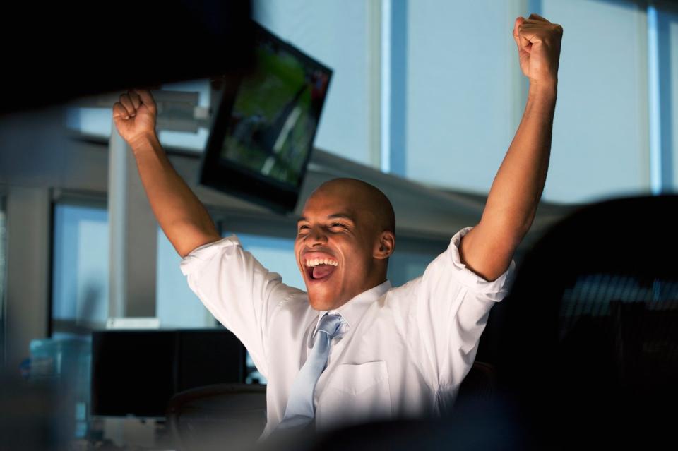 Person looking at computer screen and cheering because stock market has risen.