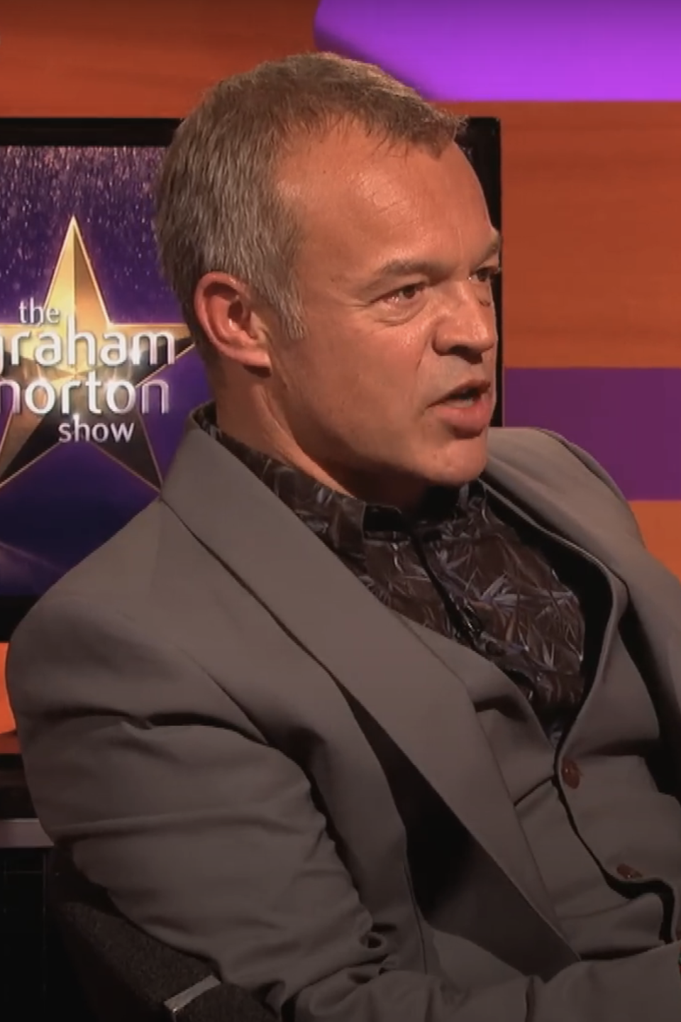 Graham Norton in a suit, seated on 