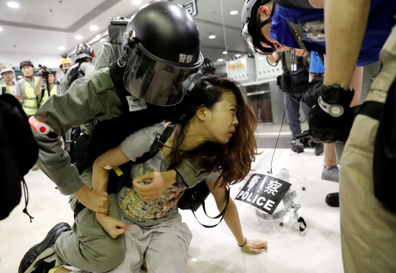 A woman is detained by riot police at a shopping mall in Tai Po in Hong Kong