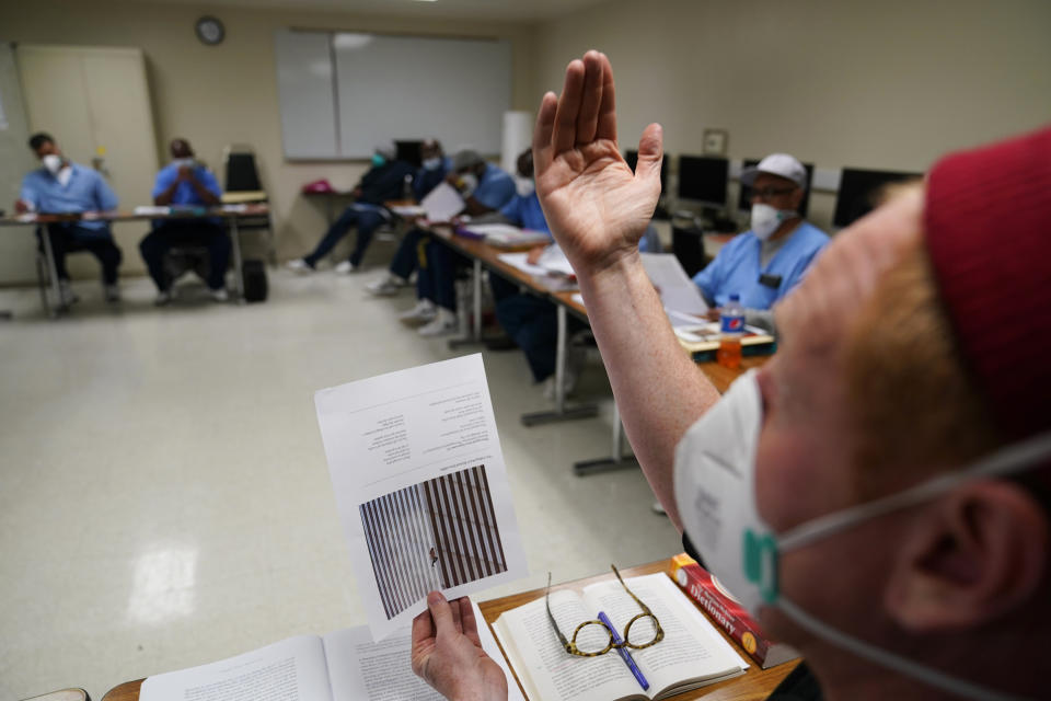 Instructor Douglas Arnwine gestures while talking about the photograph "The Falling Man," to his incarcerated students during a Mount Tamalpais College English class called Cosmopolitan Fictions at San Quentin State Prison on April 12, 2022, in San Quentin, Calif. The community college, the first in California with a campus inside a prison, is the latest addition to San Quentin's numerous rehabilitation programs that have made it a desired destination for inmates throughout the state. (AP Photo/Eric Risberg)