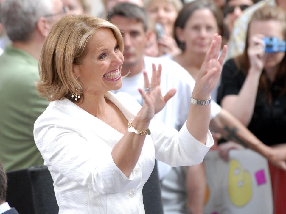 Katie Couric smiling and waving to fans.