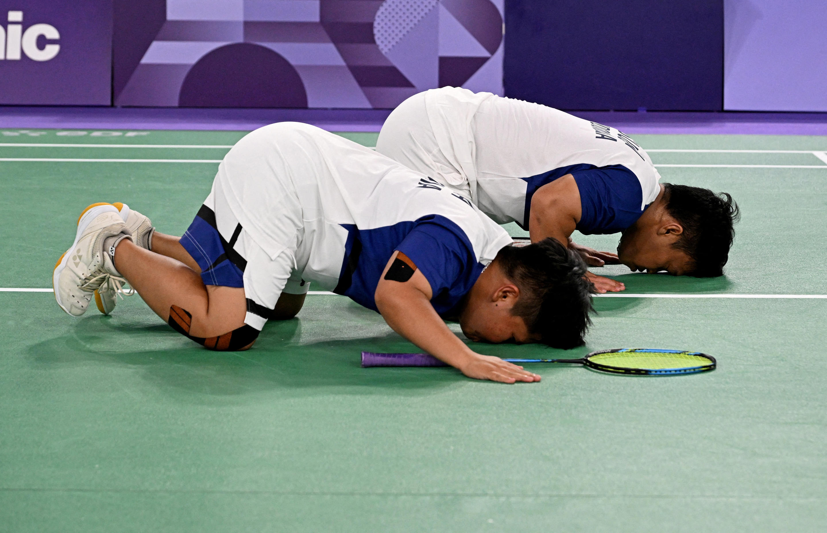 Two players bend over on the field.