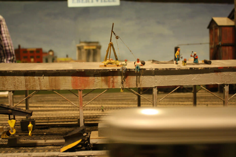 Workers on a roof as a trains speeds along. After 67 years in the Liberty Village location, The Model Railroad Club of Toronto will be moving to make way for a condo.