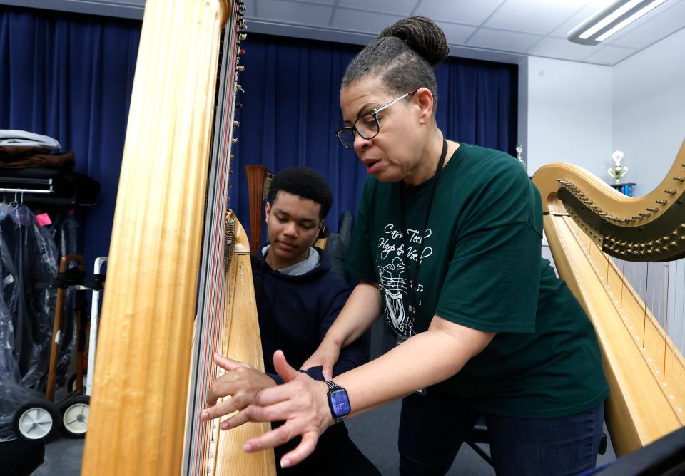 Ahmari Flowers, 15, a sophomore at Cass Technical High School works with Lydia Cleaver on his fingering of harp strings in her class on Friday, March 24, 2023.Cleaver, the director of the school's harp program and an alum of the school, oversees the students and the thirteen harps as they approach their centennial year of the program.