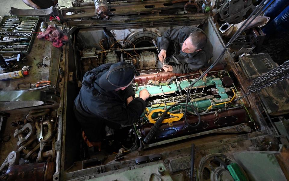 Members of the repair battalion of the 3rd Tank Brigade repair an armoured vehicle at a workshop in the Kharkiv region - SERGEY BOBOK/AFP