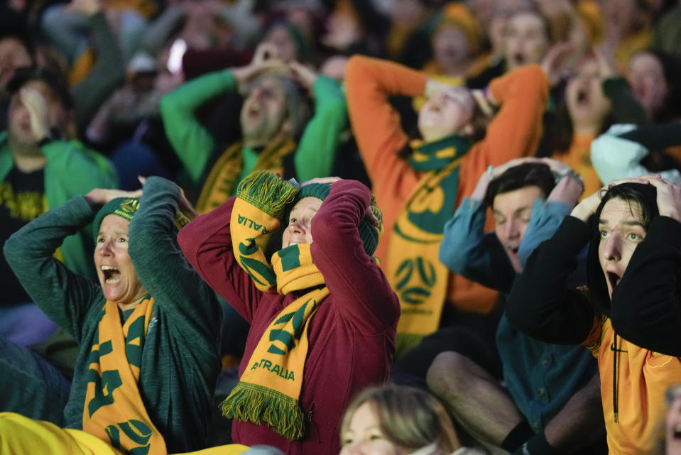 Supporters react as they watch the Australia versus France Women's World Cup quarterfinal soccer match on giant screens from Brisbane outside Stadium Australia ahead of the England and Colombia quarterfinal in Sydney, Australia, Saturday, Aug. 12, 2023. (AP Photo/Rick Rycroft)