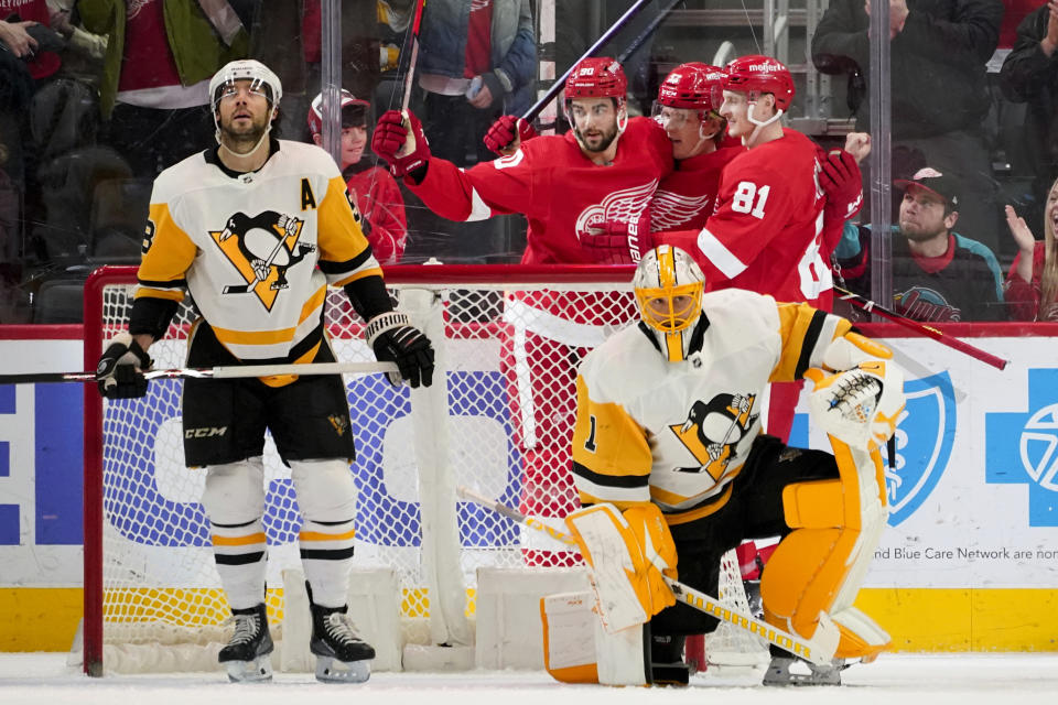 Detroit Red Wings right wing Jonatan Berggren, rear center, celebrates his goal with Joe Veleno (90) and Dominik Kubalik (81) as Pittsburgh Penguins defenseman Brian Dumoulin (8) and goaltender Casey DeSmith (1) look on in the first period of an NHL hockey game Tuesday, March 28, 2023, in Detroit. (AP Photo/Paul Sancya)