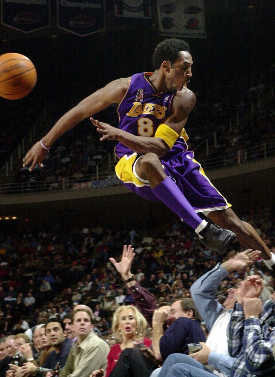 Los Angeles Lakers' Kobe Bryant jumps over a row of fans after saving the ball from going out of bounds in the second half of the Lakers 107-101 win over the Houston Rockets in Houston, Dec. 20, 2001. Bryant, a five-time NBA champion and a two-time Olympic gold medalist, died in a helicopter crash in California on Sunday, Jan. 26, 2020. (AP Photo/Pat Sullivan)