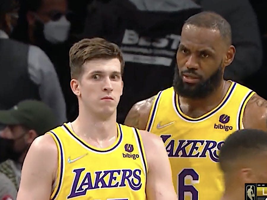 Austin Reaves looks confused as LeBron James speaks to him during a game.