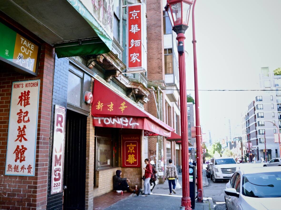 Gain Wah, pictured under its red awning, was forced to close last Friday after a fire that started in one of the SRO rooms above seriously damaged the restaurant. (Rafferty Baker/CBC - image credit)