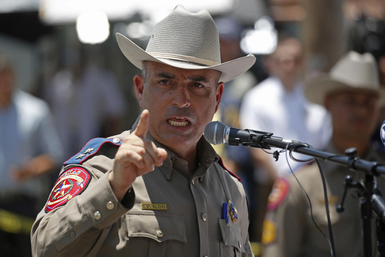 Victor Escalon points while standing behind a microphone.