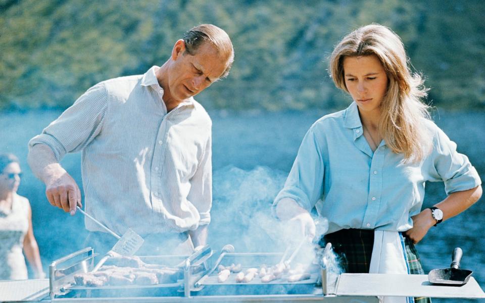 The Duke of Edinburgh and Princess Anne preparing a barbecue on the Estate at Balmoral Castle in 1972 - Credit: Lichfield/Getty Images