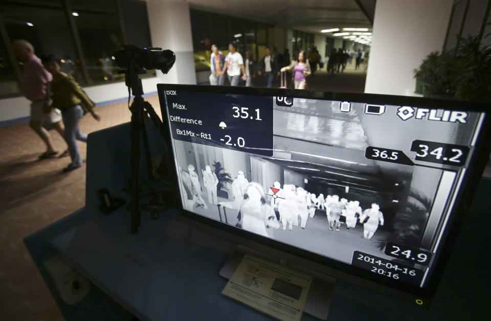 FILE- In this Wednesday, April 16, 2014, file photo, passengers walk past a thermal scanner at the medical quarantine area at the arrival section of Manila's International Airport in Paranaque, south of Manila, Philippines. One expert says recent outbreaks of MERS in Saudi Arabia and the United Arab Emirates that led to more than 20 infections, many among health-care workers, “have put us into uncharted territory.” (AP Photo/Aaron Favila)