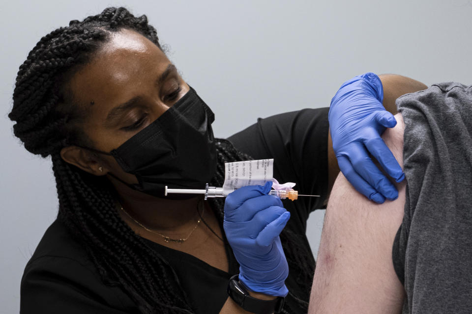 Cole Smith receives a Moderna variant vaccine shot from clinical research nurse Tigisty Girmay at Emory University's Hope Clinic, on Wednesday afternoon, March 31, 2021, in Decatur, Ga. Smith, who received Moderna's original vaccine a year ago in a first-stage study, said returning wasn’t a tough decision. “The earlier one, it was a great success and, you know, millions of people are getting vaccinated now. ... If we’re helping people with the old one, why not volunteer and help people with the new one?” (AP Photo/Ben Gray)