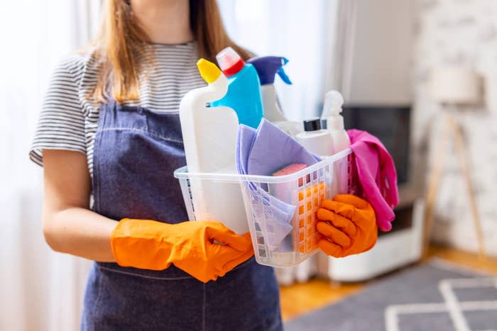 Woman carrying a basket of cleaning supplies