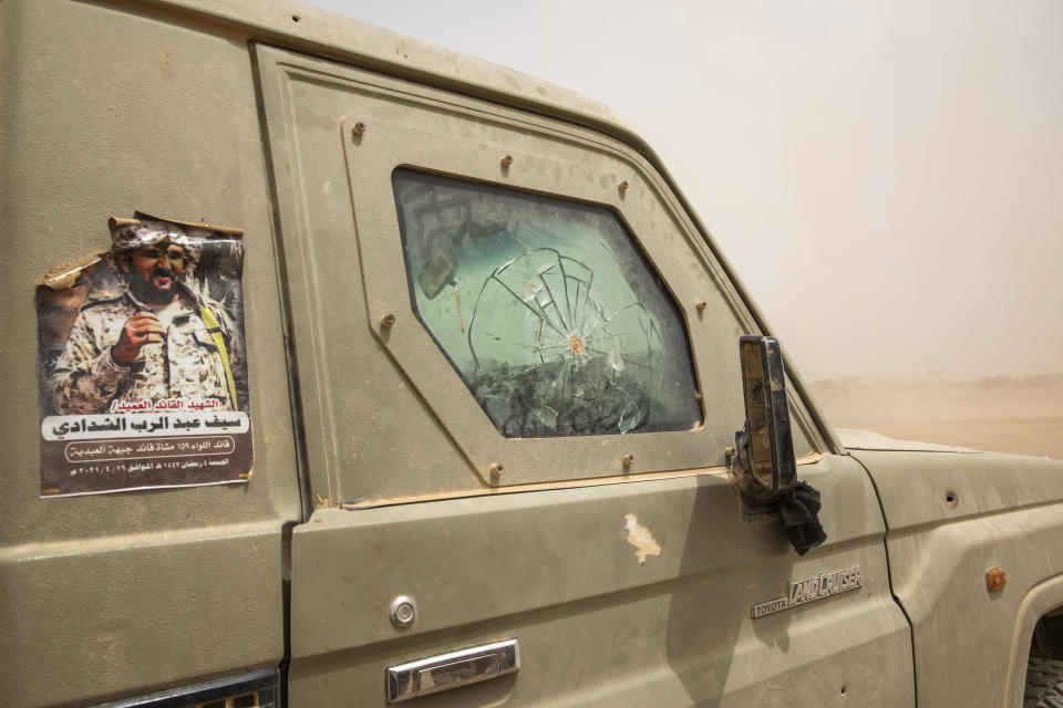 Yemeni fighters drive their damaged armored vehicle with a poster of a commander brigadier general and Arabic that reads, "martyr commander brigadier general Self Abd al-Rab al-Shadady," who was killed in clashes with Houthi rebels, on the Mass front line, in Marib, Yemen, Saturday, June 19, 2021. On the most active front line in Yemen's long civil war, the months-long battle for the city of Marib has become a dragged-out grind with a steady stream of dead and wounded from both sides. (AP Photo/Nariman El-Mofty)