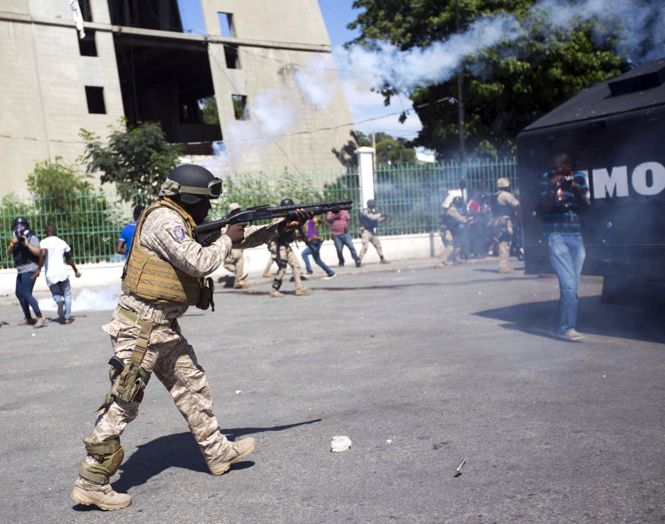 A police officer fires his shotgun during a protest demanding to know how Petro Caribe funds have been used by the current and past administrations, in Port-au-Prince, Haiti, Wednesday, Oct. 17, 2018. Much of the financial support to help Haiti rebuild after the 2010 earthquake comes from Venezuela's Petro Caribe fund, a 2005 pact that gives suppliers below-market financing for oil and is under the control of the central government. (AP Photo/Dieu Nalio Chery)