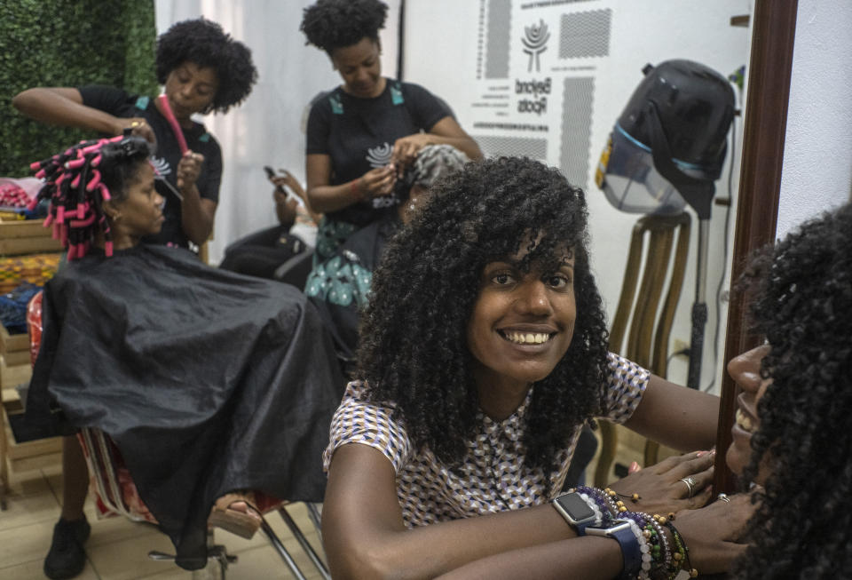 Adriana Heredia posa frente a sus clientes en Beyond Roots, una empresa privada que incluye una tienda de ropa, un salón de belleza especializado en cabello afro y varios otros proyectos culturales en La Habana, Cuba, el martes 6 de junio de 2023. (AP Foto/Ramón Espinosa)