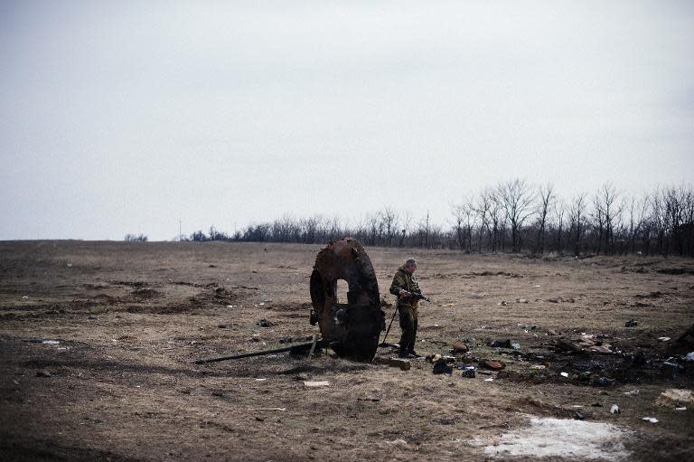 A pro-Russian rebel looks at parts of a destroyed APC near the village of Logvinove near the eastern Ukrainian town of Debaltseve on March 26, 2015