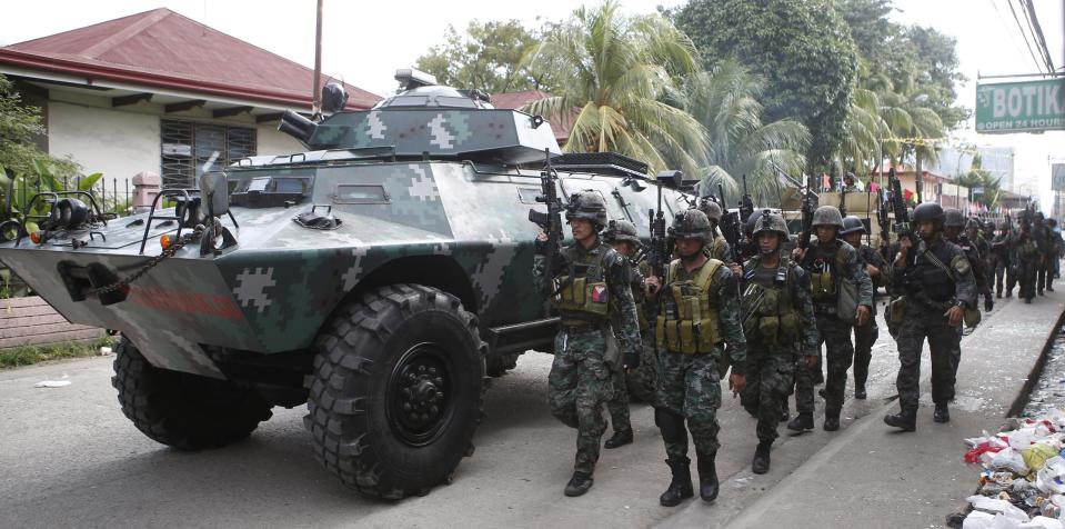 Members of the elite Special Action Police walk next to an armoured vehicle as they reinforce soldiers battling Muslim rebels from the MNLF in Zamboanga city, in southern Philippines