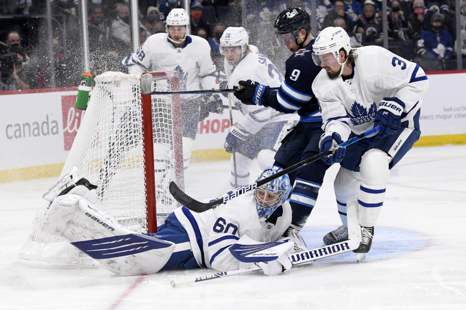 Winnipeg Jets' Andrew Copp (9) looks for the puck as Toronto Maple Leafs goaltender Joseph Woll (60) covers it with Maple Leafs' Justin Holl (3) defending during the second period of NHL hockey game action in Winnipeg, Manitoba, Sunday, Dec. 5, 2021. (Fred Greenslade/The Canadian Press via AP)