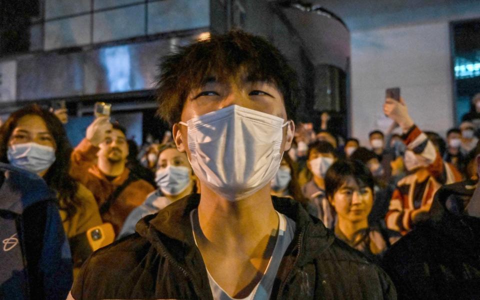 People gather on a street in Shanghai on November 27, 2022, where protests against China's zero-Covid policy took place the night before following a deadly fire in Urumqi, the capital of the Xinjiang region. - HECTOR RETAMAL/AFP