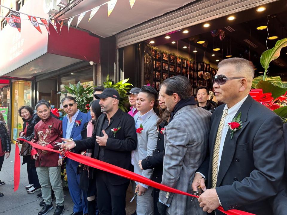 阿克代尼茲(前排左五)28日新店入駐法拉盛市中心羅斯福大道，當日贈送1000片披薩，回饋社區。(記者牟蘭／攝影)