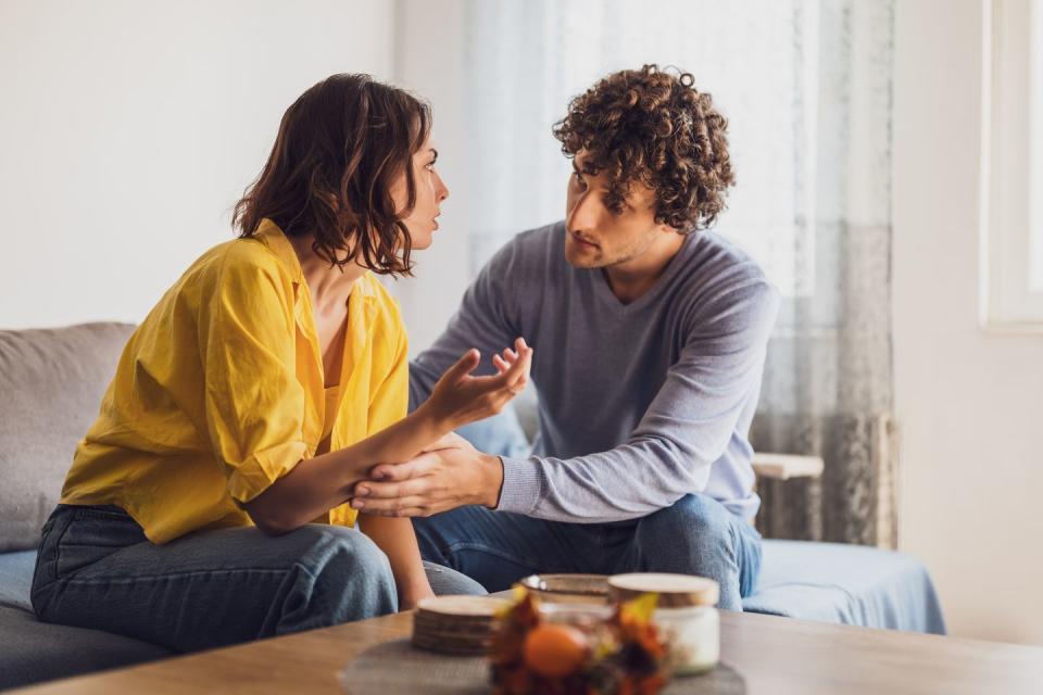 man and woman are sitting at sofa and arguing relationship problems