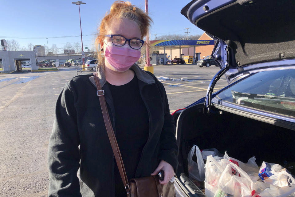 Hairdresser Chelsea Woody stands outside her car at a grocery store Tuesday, Jan. 11, 2022, in Charleston, W.Va. For the first time in half a year, families on Jan. 14, are going without a monthly deposit from the federal child tax credit. Woody, a single mother, relied on the check to help raise her young son. (AP Photo/John Raby)