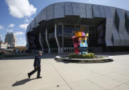 A man wearing a mask walks past the Golden 1 Center, home of the Sacramento Kings in Sacramento, Calif., Thursday, March 19, 2020. Because of the coronavirus, public health officials in Sacramento County issued a shelter-in-place order on Thursday. (AP Photo/Rich Pedroncelli)