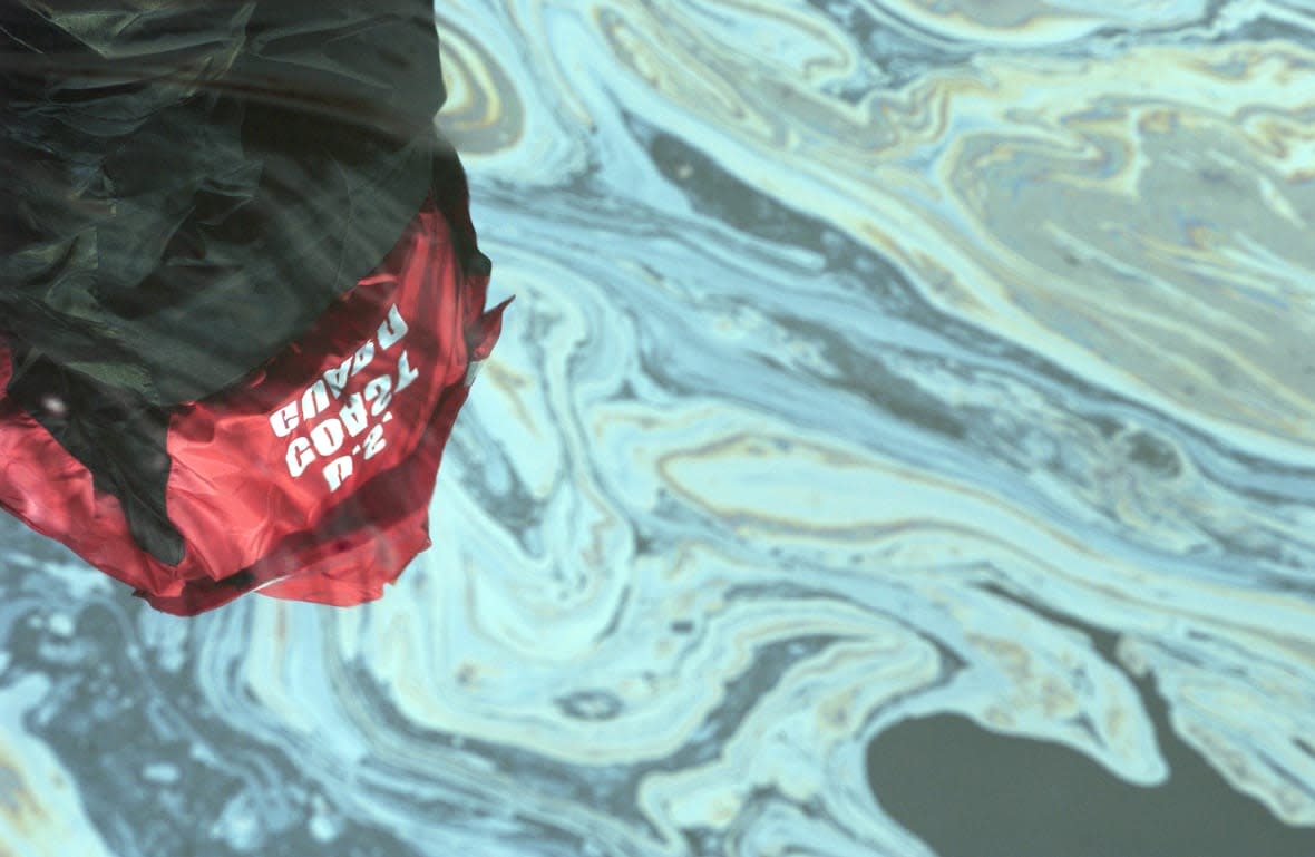 In this handout provided by the U.S. Coast Guard, the image of Chief Petty Officer Britton E. Henderson, Atlantic Strike Team, is reflected in an oil spill on November 28, 2004 in the Delaware River near Philadelphia, Pennsylvania. (Photo by Mike Lutz/USCG via Getty Images)