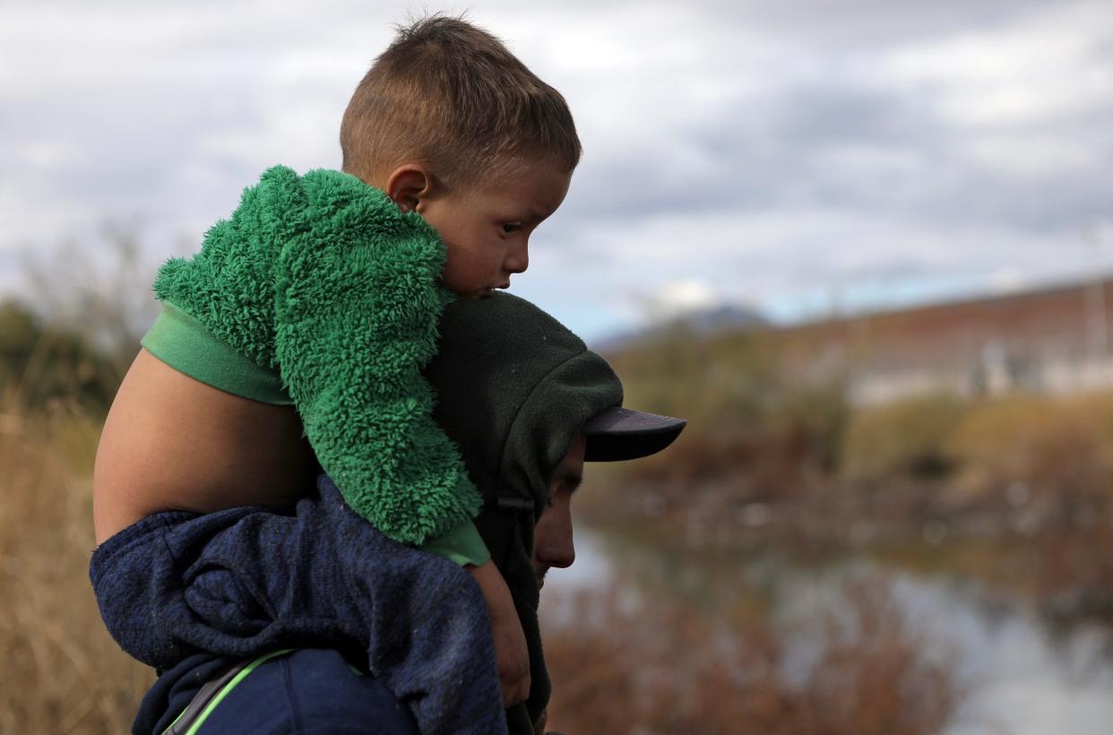 A migrant with a child on his shoulders arrives to cross the Rio Grande in the into the US, in Ciudad Juarez, Chihuahua State, Mexico, on January 2, 2024.