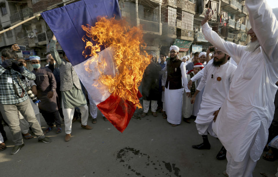 Supporters of religious group burn a representation of a French flag during a rally against French President Emmanuel Macron and republishing of caricatures of the Prophet Muhammad they deem blasphemous, in Karachi, Pakistan, Friday, Oct. 30, 2020. Muslims have been calling for both protests and a boycott of French goods in response to France's stance on caricatures of Islam's most revered prophet. (AP Photo/Fareed Khan)