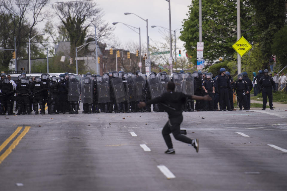 BALTIMORE, MD - APRIL 27: A man runs in front of officers during a protest for Freddie Gray near Mondawmin Mall in Baltimore, MD on Monday April 27, 2015. Gray died from spinal injuries about a week after he was arrested and transported in a police van. (Photo by Jabin Botsford/The Washington Post via Getty Images)