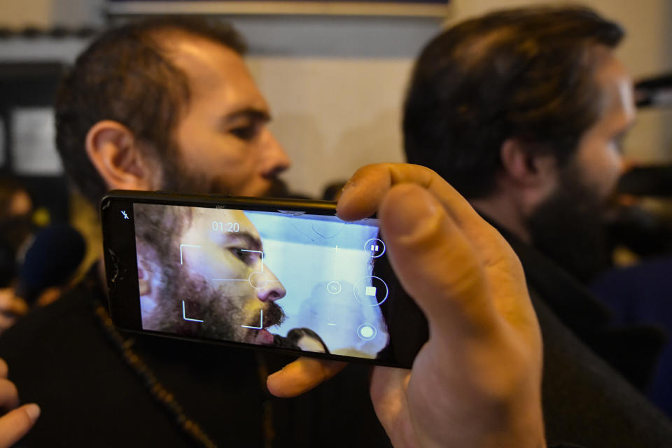 Andrew Tate, left, seen on the screen of a mobile phone and his brother Tristan leave a police detention facility in Bucharest, Romania, after his release from prison on Friday March 31, 2023. An official on Friday said Tate, the divisive internet personality who has spent months in a Romanian jail on suspicion of organized crime and human trafficking, has won an appeal to replace his detention with house arrest. (AP Photo/Alexandru Dobre)