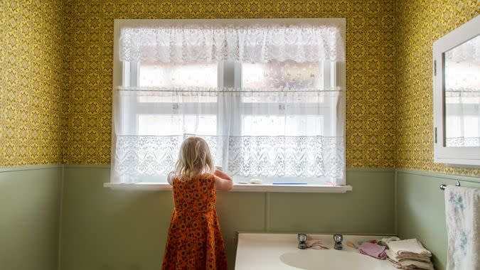 Young girl alone exploring the bathroom of a 1970s house.