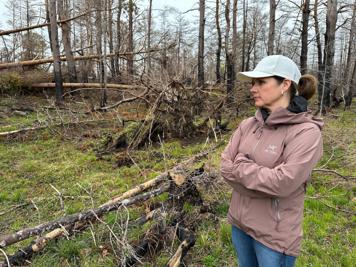 Samantha Brannen is shown at her Clyde River, N.S., home alongside burned and uprooted trees damaged by the Shelburne County wildfire that started on May 26, 2023. (CBC - image credit)