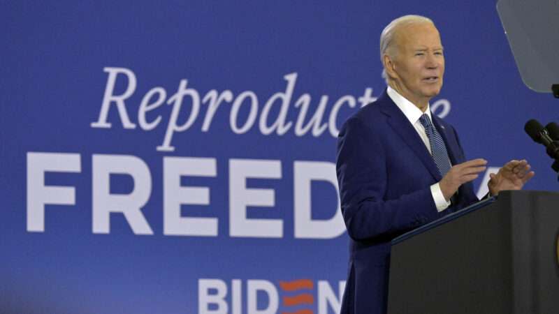 Joe Biden standing in front of a banner that says 'reproductive freedom'