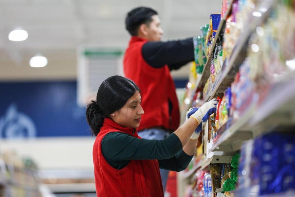 Employees help stock the shelves with products at the new Super G Mart in Pineville.