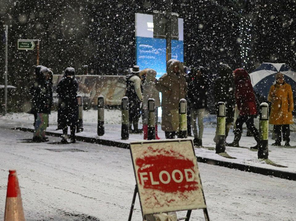 People cross a bridge over the River Mersey as snow falls in East Didsbury, Manchester, where homes are being evacuated due to risk of floodingPeter Byrne/PA