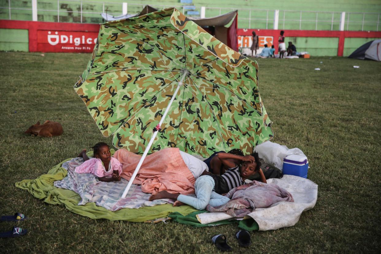 People rest after spending the night at a soccer field following Saturday's 7.2 magnitude earthquake in Les Cayes, Haiti, Sunday, Aug. 15, 2021.