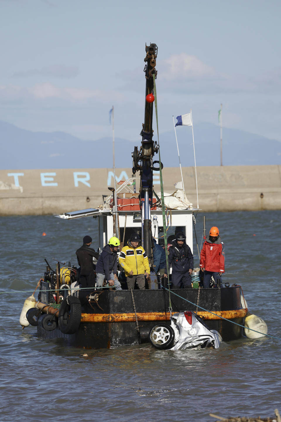 Rescuers remove damaged car from a sea after heavy rainfall triggered landslides that collapsed buildings and left as many as 12 people missing, in Casamicciola, on the southern Italian island of Ischia, Sunday, Nov. 27, 2022. Firefighters are working on rescue efforts as reinforcements are being sent from nearby Naples, but are encountering difficulties in reaching the island either by motorboat or helicopter due to the weather. (AP Photo/Salvatore Laporta)