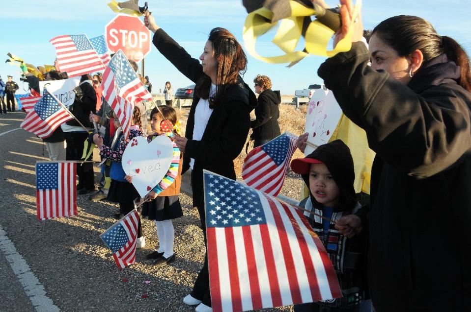 Supporters of Berrendo Middle School hold welcome backs signs and balloons while waving American flags and yellow ribbons, greet returning students, parents and teachers back to the school, Thursday, Jan. 16, 2014, in Roswell, N.M. Two days after the shooting that involved three students and forced the evacuation and closing of the school. (AP Photo/Roswell Daily Record, Mark Wilson)